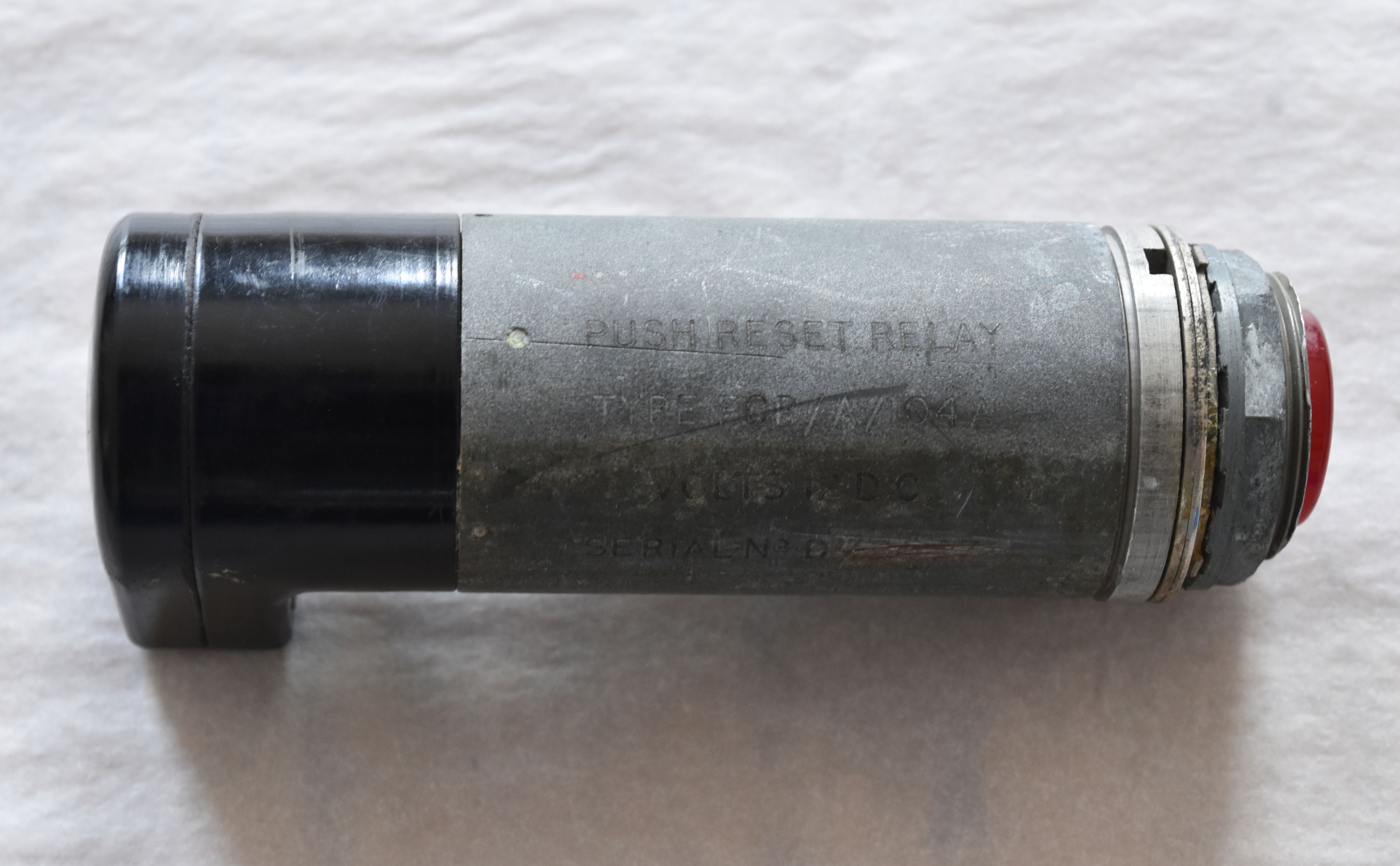 A push reset relay, a horizontal cylindrical object with a red button at the left side. Inscribed with the words 'push reset relay'. 